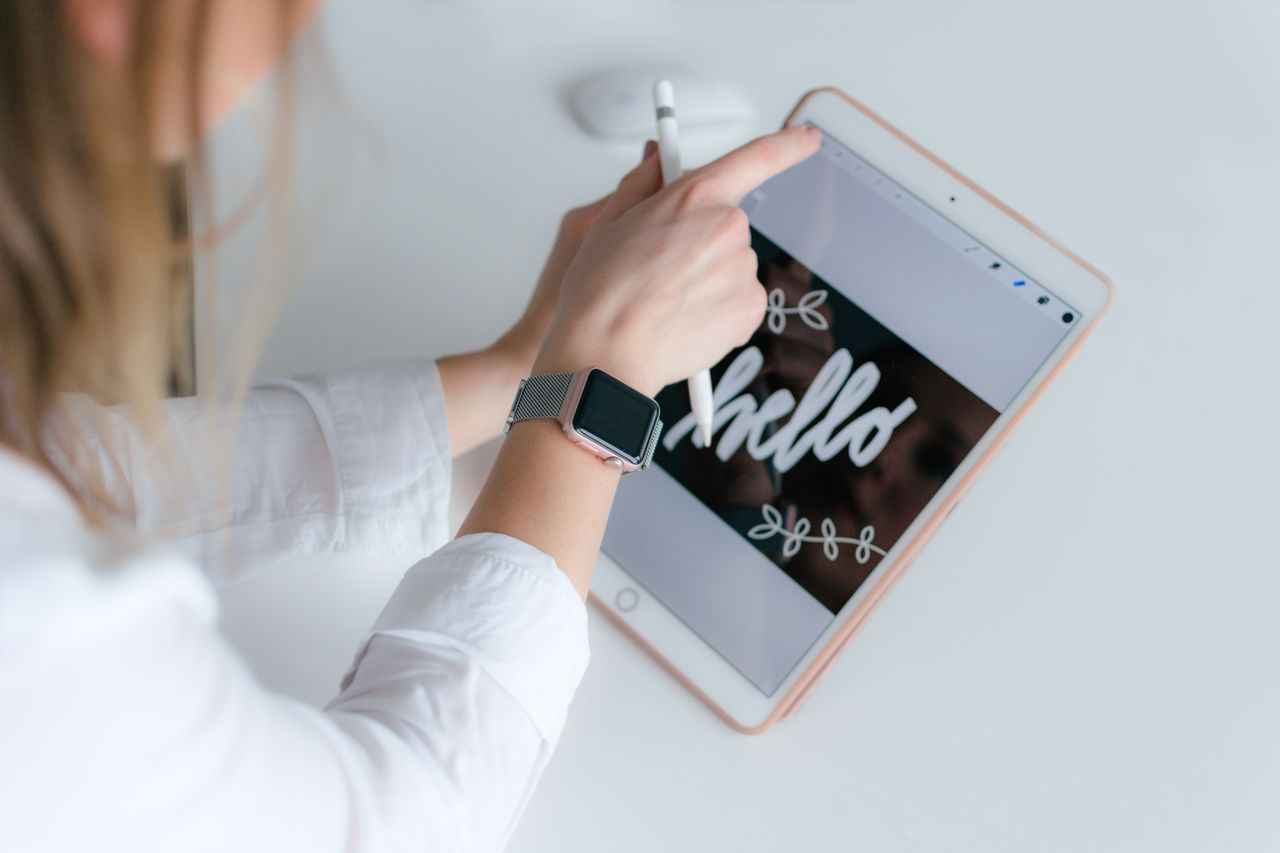 who-we-are A woman interacts creatively with a tablet and stylus indoors, using technology for design.